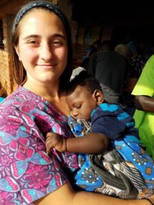 Julia from the US team holds a baby who was brought to our clinic